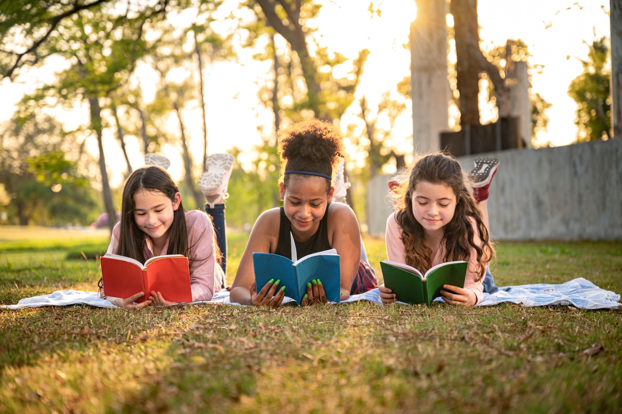 Student girl lie down reading book with sunset in the school park Raconte-moi une histoire
